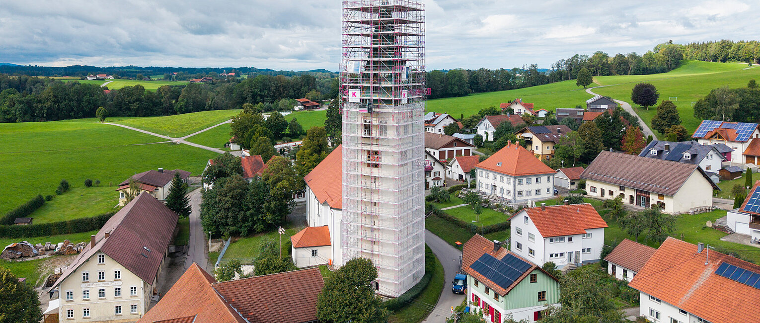 Vollständig eingewickelter Kirchturm mit Fassadengerüst von Kaufmann Gerüstbau für Sanierungsarbeiten in Merazhofen