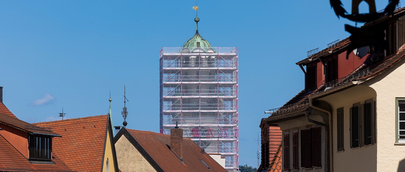 Historische Innenstadt mit Fachwerkhäusern und einem Kirchturm, der von einem Gerüst umgeben ist.